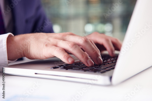 Close up of businessman?s hands using the keypad of a laptop