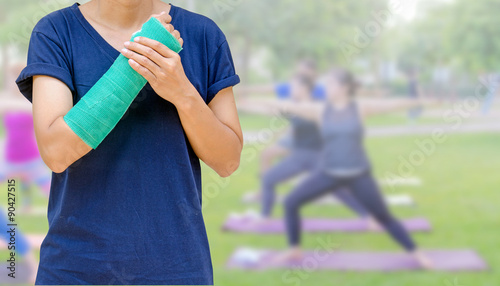 broken arm with green cast on blurred woman fitness group - yoga