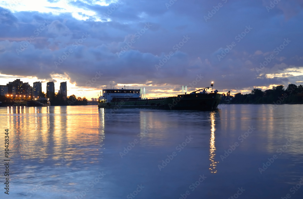 View of Neva River and river cargo ship at sunset.
