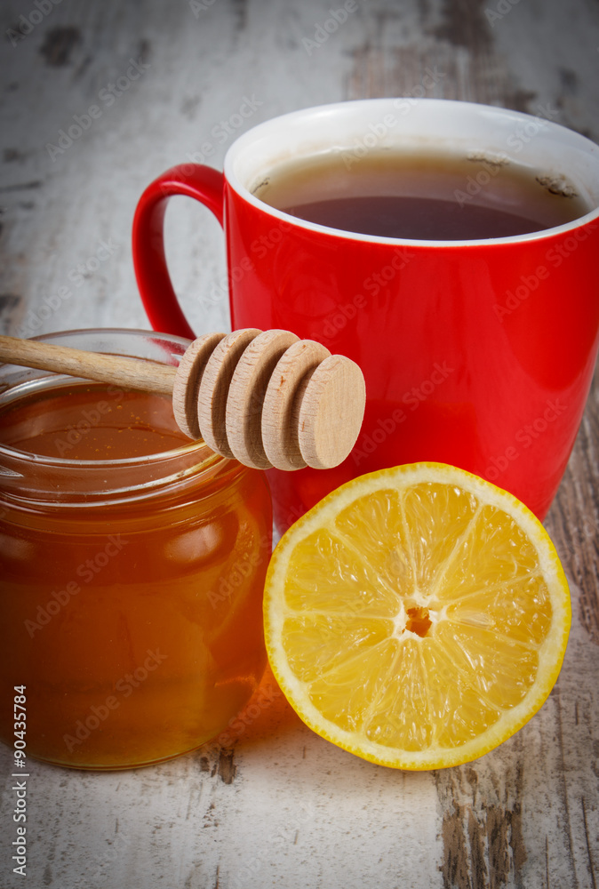 Fresh lemon with honey and cup of tea on wooden table, healthy nutrition
