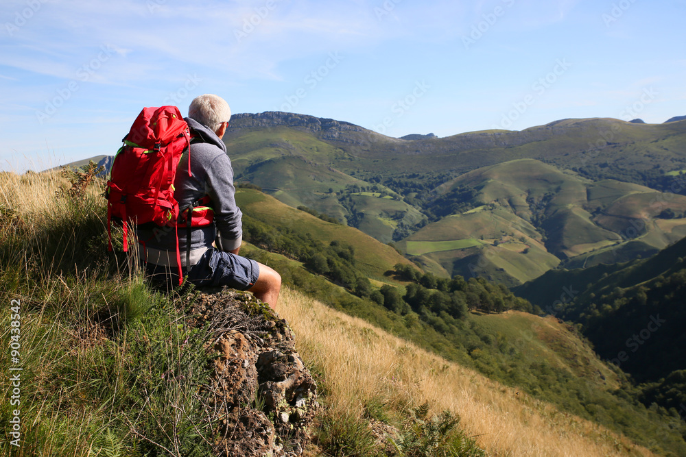Fototapeta premium Hiker sitting on a rock admiring Basque Country scenery