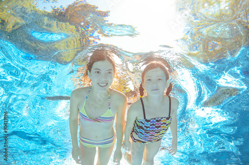 Children swim in pool or sea underwater, happy active girls have fun in water, kids sport 