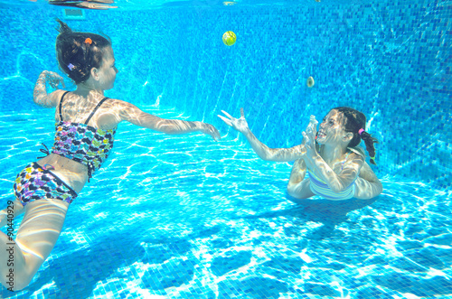 Children swim in pool underwater, happy active girls have fun in water