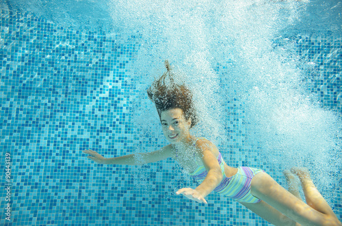 Girl jumps and swims in pool underwater  happy active child has fun in water  