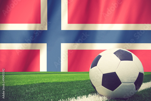 Soccer ball and national flag of Norway lies on the green grass