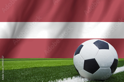 Soccer ball and national flag of Latvia lies on the green grass