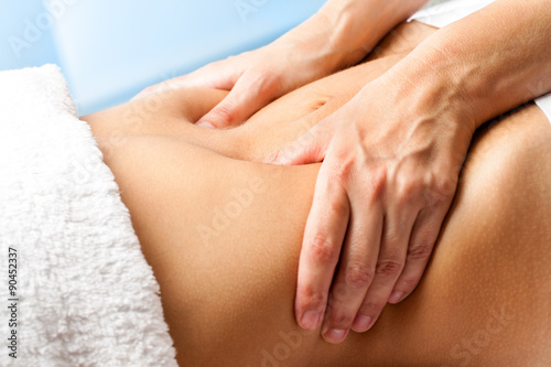 Macro close up of hands massaging female abdomen.