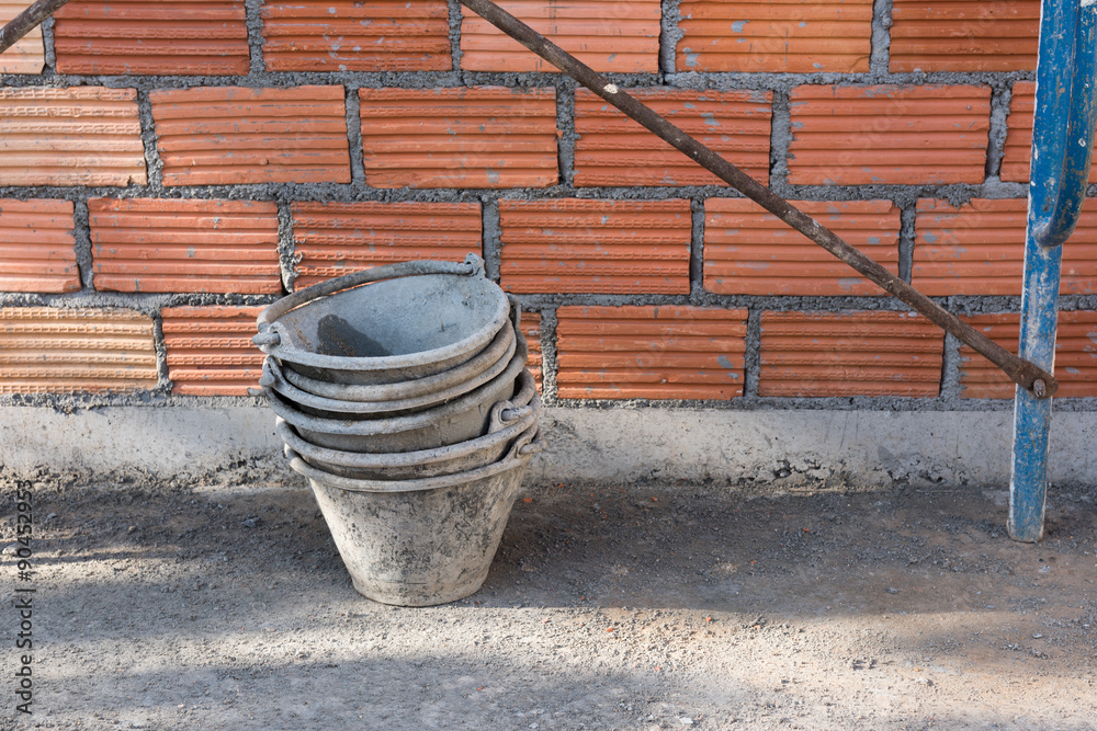 Cement buckets and red brick wall background at construction sit Cement buckets and red brick wall background at construction sit
