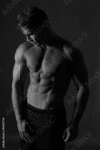 Male Fitness Model. Low key lighting portrait of half naked muscular man. Black and white studio shot isolated on white.
