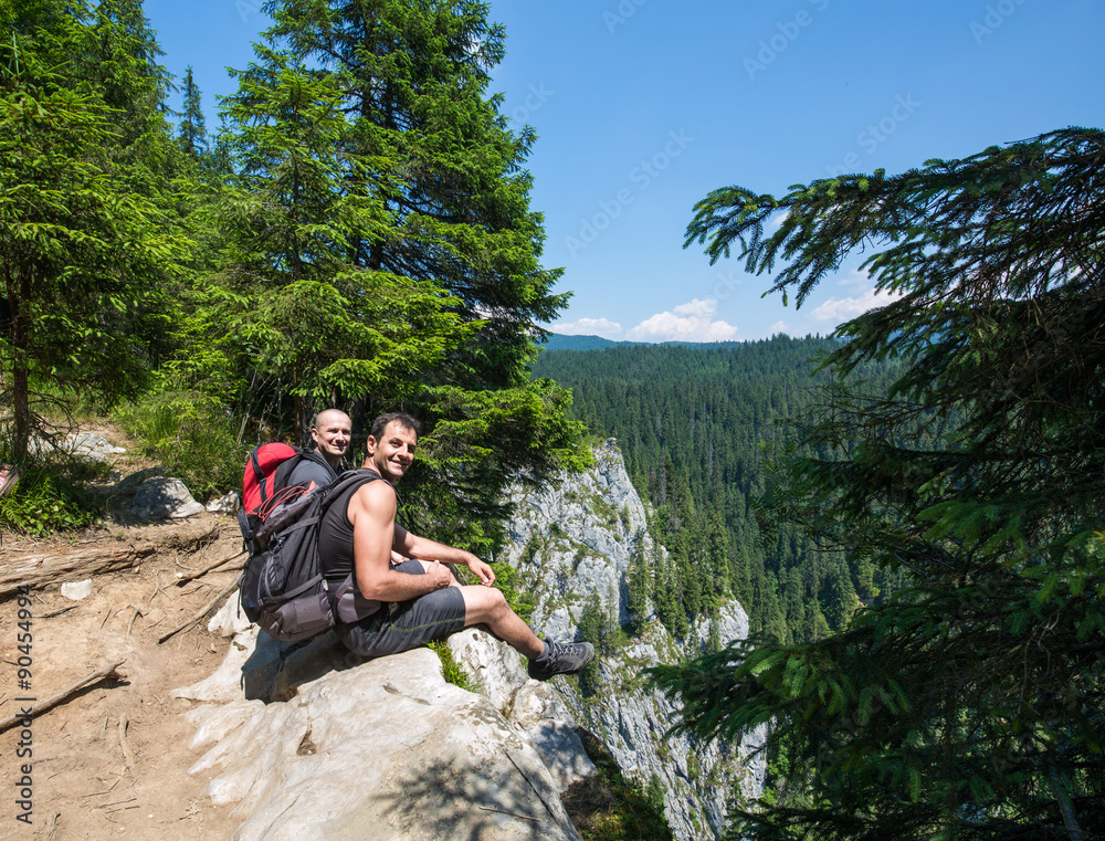 Hikers sitting on the edge of a very high cliff Hikers sitting on the edge of a very high cliff