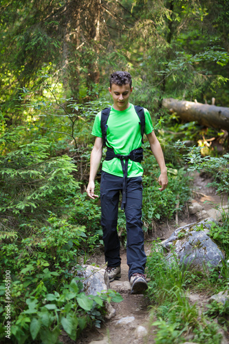 Teenager boy waking through a forest trail