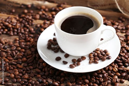 Cup of coffee with coffee beans on a brown wooden background