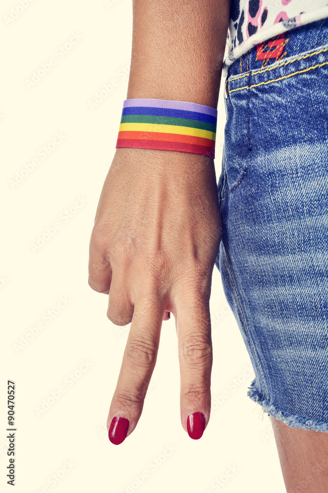 woman making the V sign, with a bracelet patterned as the rainbo