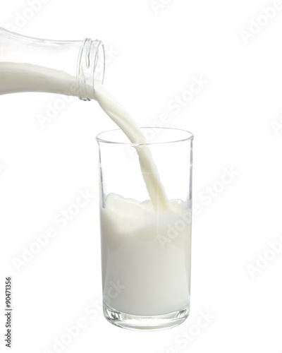 Pouring milk from bottle into glass on white background.