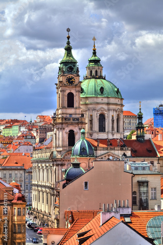 Blick über die leuchtenden Dächer von Prag in der Tschechischen Republik mit einem dramatischen Wolkenhimmel und Blick auf die Kirche des heiligen St. Nikolaus