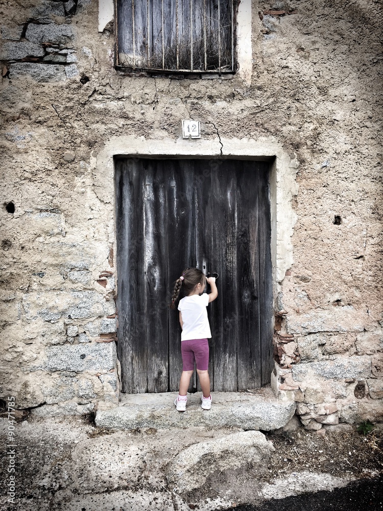 Cute little girl standing in front of an old wood door Stock Photo ...