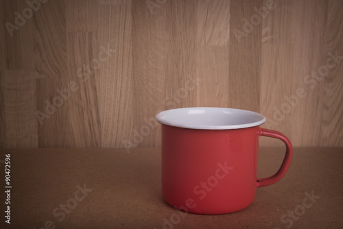 Vintage red mug on wooden board background