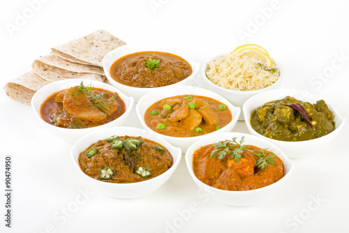 Vegetarian Curries - Selection of South Asian vegetarian curries in white bowls. Paneer Makhani, Palak Paneer, Aloo Matar, Baigan Bharta, Chilli Potatoes and Bhindi Masala, Pilau Rice and Chapattis.
