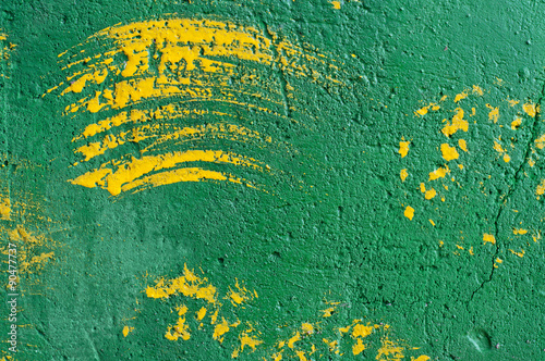 Background of brush strokes of yellow paint on a green wall photo