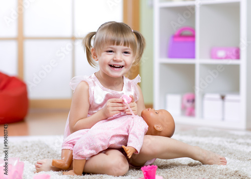 Papier peint Kid girl plays with doll at home in the children room