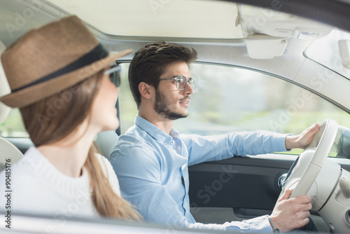 Young couple in his car, happy to drive on a country road