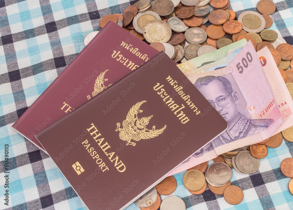 Passport and Banknotes of Thailand currency on the pile of coins baht currency, on the loincloth silk background. Passport and Banknotes of Thailand currency on the pile of coins baht currency, on the loincloth silk background.
