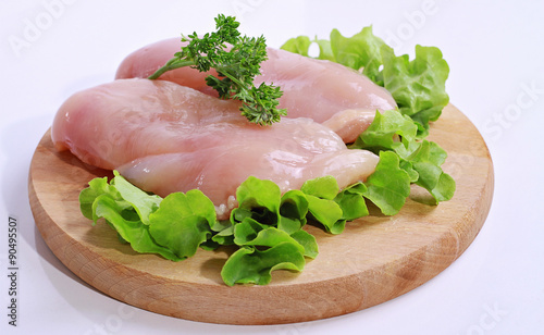 Raw chicken breast fillets decorated with salad on wooden cutting board. Diet food, healthy lifestyle