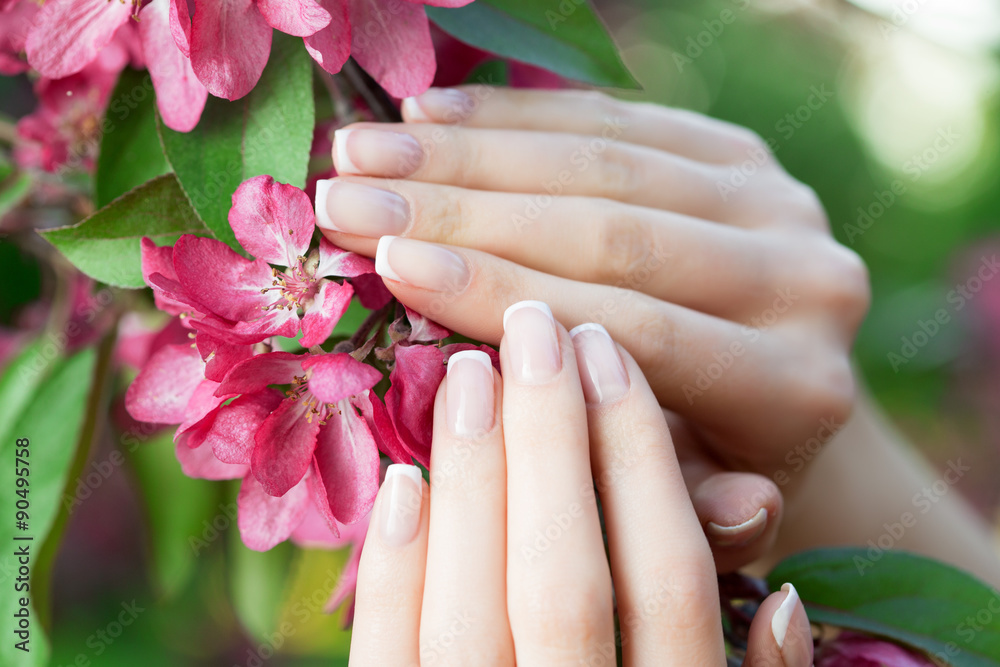 Fototapeta premium Hands with a stunning manicure on flowers