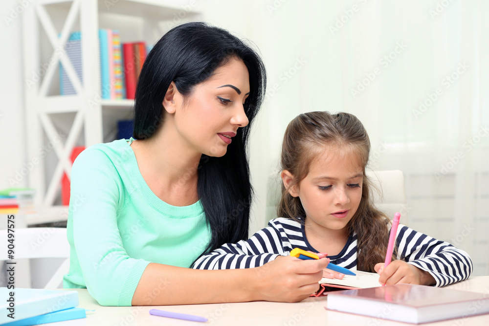 Beautiful school girl doing homework with mother at home Beautiful school girl doing homework with mother at home
