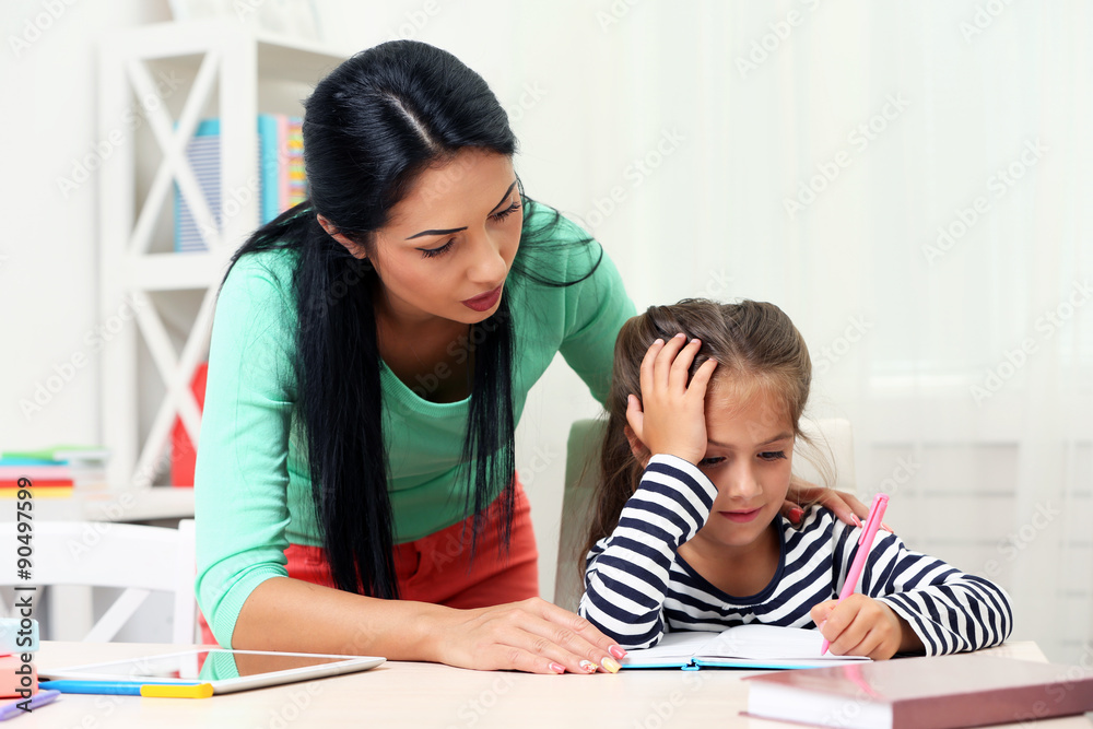 Beautiful school girl doing homework with mother at home Beautiful school girl doing homework with mother at home