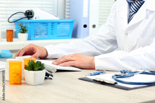 Doctor working at table in office