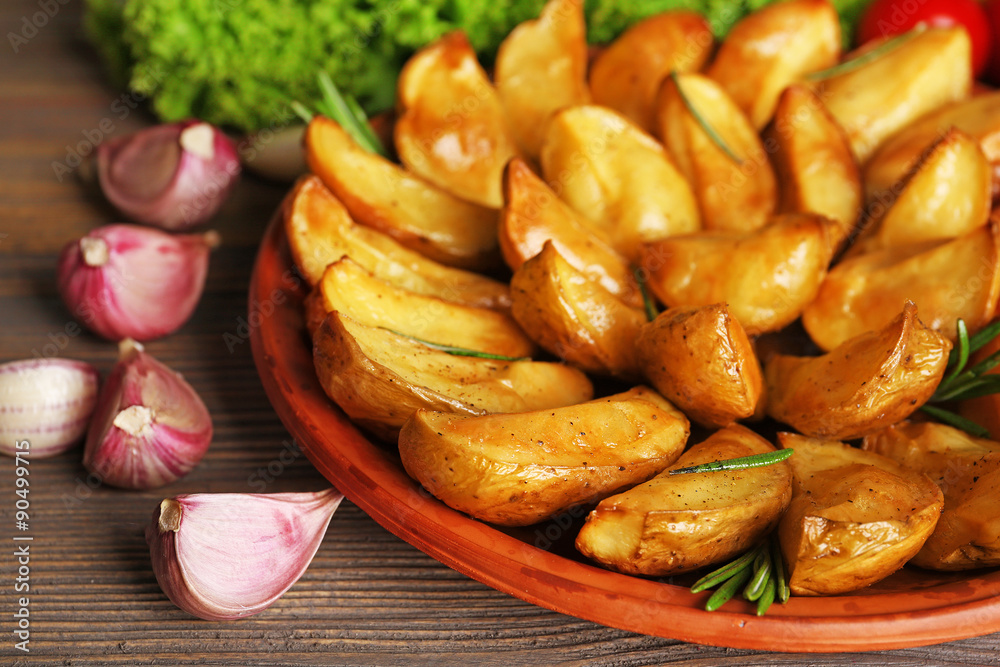 Baked potato wedges on wooden table, closeup Baked potato wedges on wooden table, closeup
