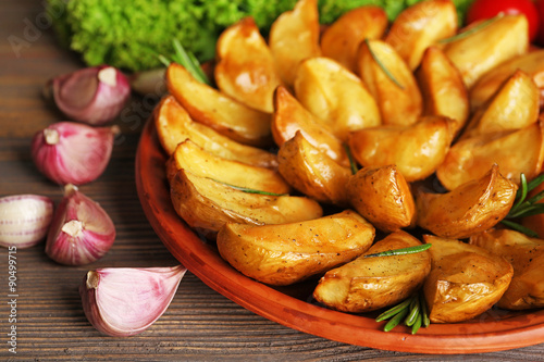 Baked potato wedges on wooden table, closeup