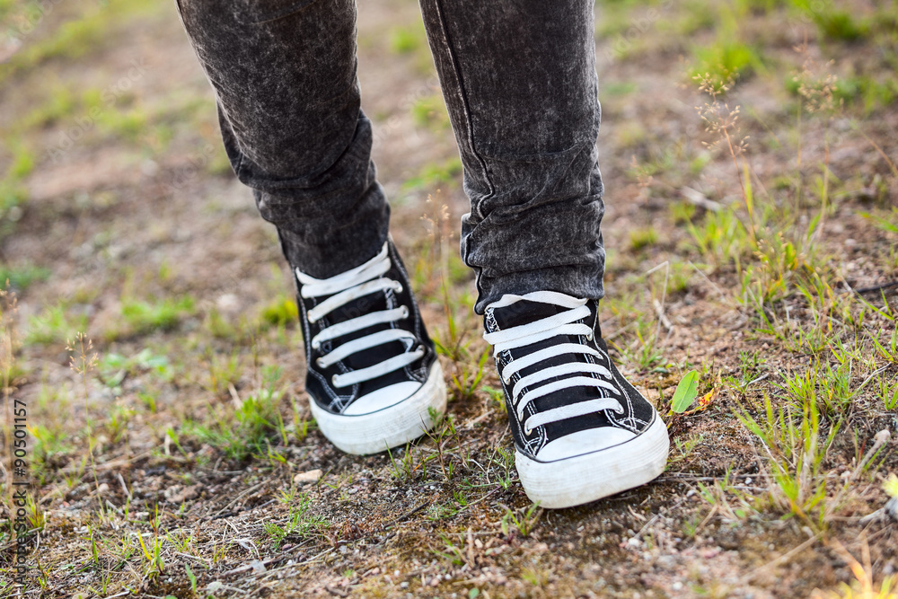 Unrecognizable person in rubber shoes walking on footpath