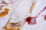 Detail of folded pancake with sugar and fruit sauce 