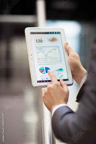 Obraz na płótnie Business person analyzing financial statistics displayed on the tablet screen w salonie