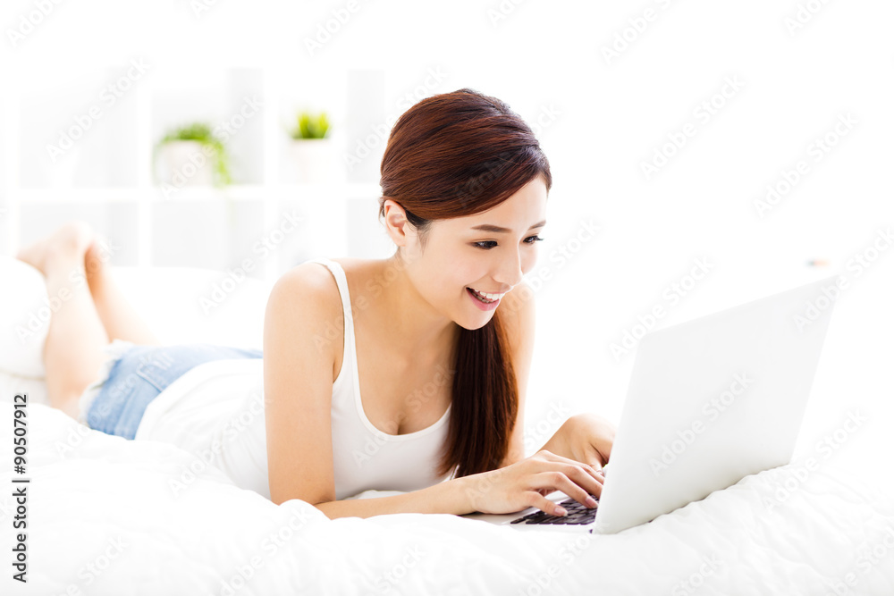 smiling young woman with laptop on the bed smiling young woman with laptop on the bed