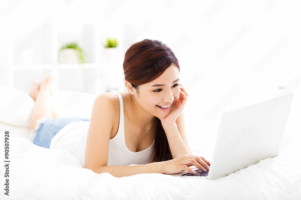 smiling young woman with laptop on the bed smiling young woman with laptop on the bed