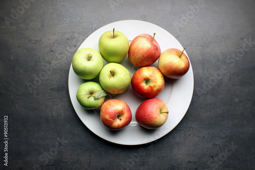 Fresh apples on big white plate and grey kitchen table background