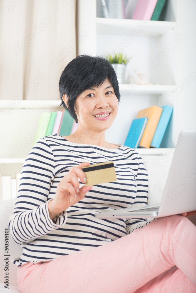 asian senior female using credit card on laptop asian senior female using credit card on laptop