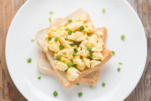 Scrambled eggs on toast, garnished with onion.