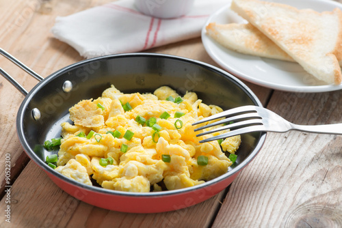 Scrambled egg served in a pan with toast.