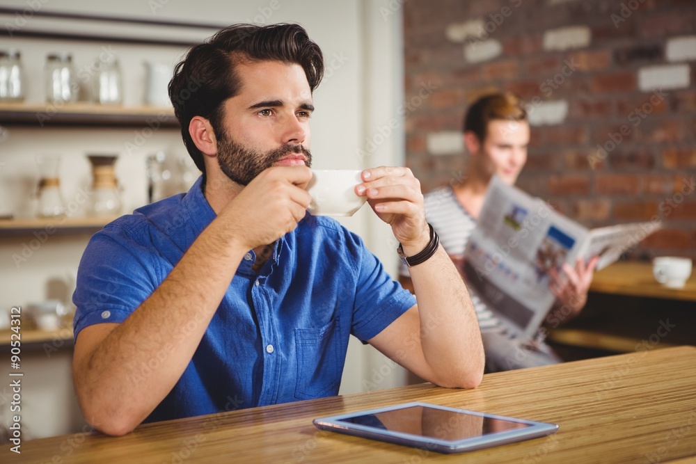 Young man having cup of coffee using tablet Young man having cup of coffee using tablet