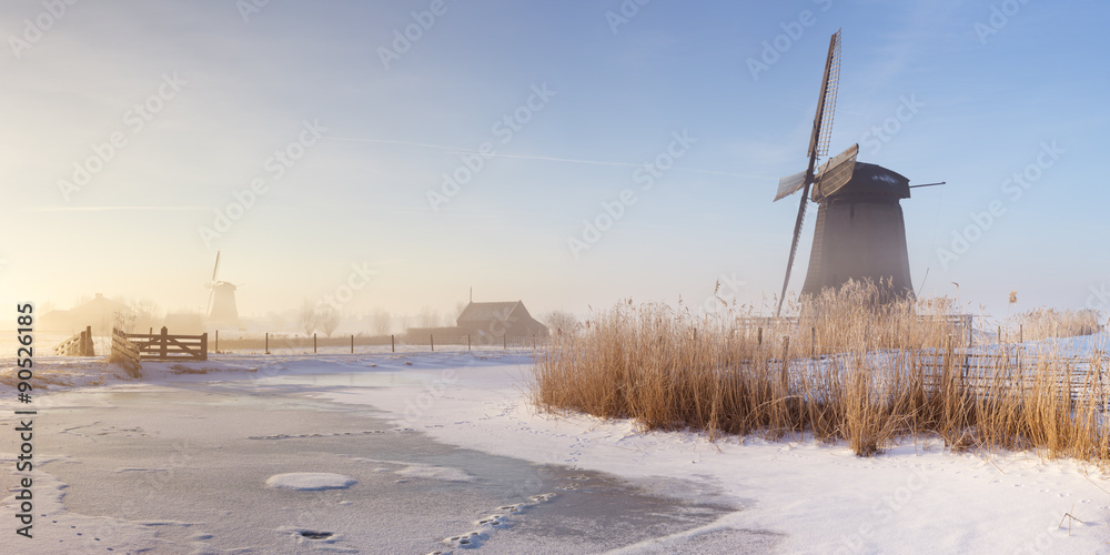 Dutch windmills in a foggy winter landscape in the morning Dutch windmills in a foggy winter landscape in the morning