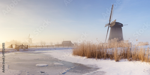 Dutch windmills in a foggy winter landscape in the morning