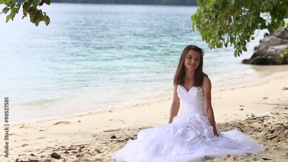 longhaired bride sits on sand and stands up against sea and island longhaired bride sits on sand and stands up against sea and island