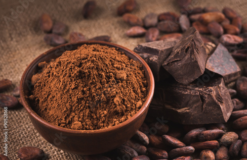 Raw cocoa beans, clay bowl  with cocoa powder, chocolate on sack