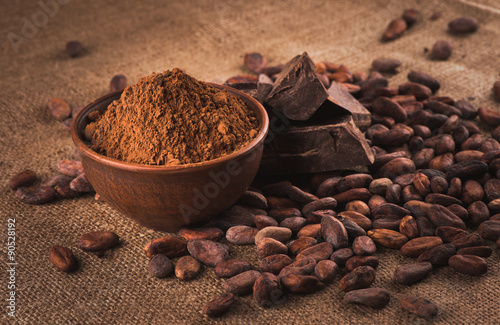 Raw cocoa beans, clay bowl  with cocoa powder, chocolate on sack