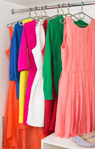 row of bright colorful dress hanging on coat hanger  shoes and h