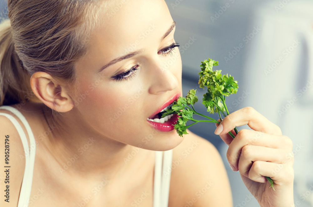 woman eating coriander at domestic kitchen woman eating coriander at domestic kitchen